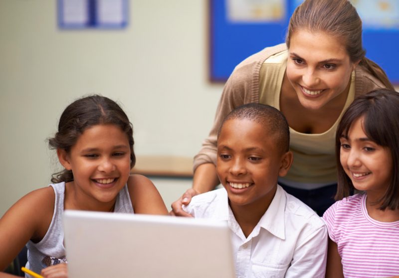 Educational Technology Online Graduate Certificate Image of Teacher Working with Children in Front of a Computer